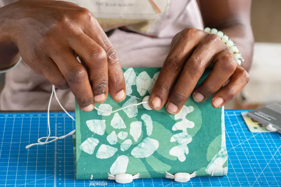 a craftsperson stitching together journals for Just Because Love Does